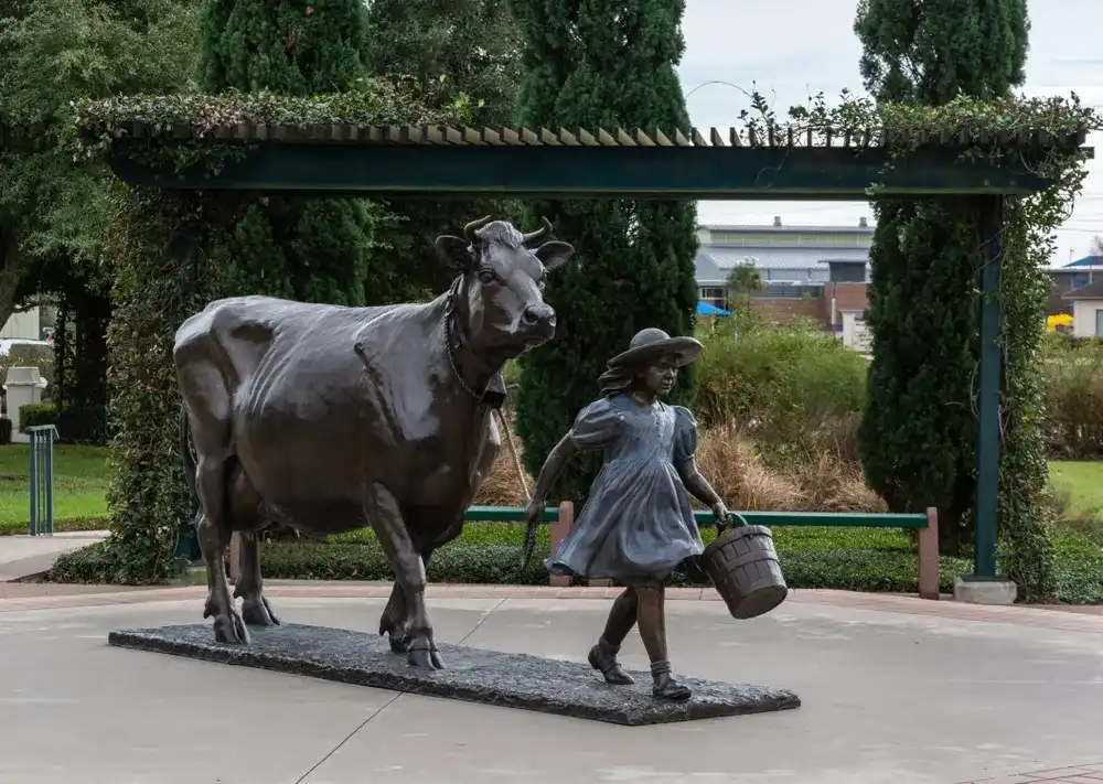 Brenham, Texas, United States of America - December 27, 2016. Monument depicting a girl with a cow in front of the Blue Bell Creameries factory in Brenham, TX. Brenham, Texas, United States of America - December 27, 2016. Monument depicting a girl with a cow in front of the Blue Bell Creameries factory in Brenham, TX.