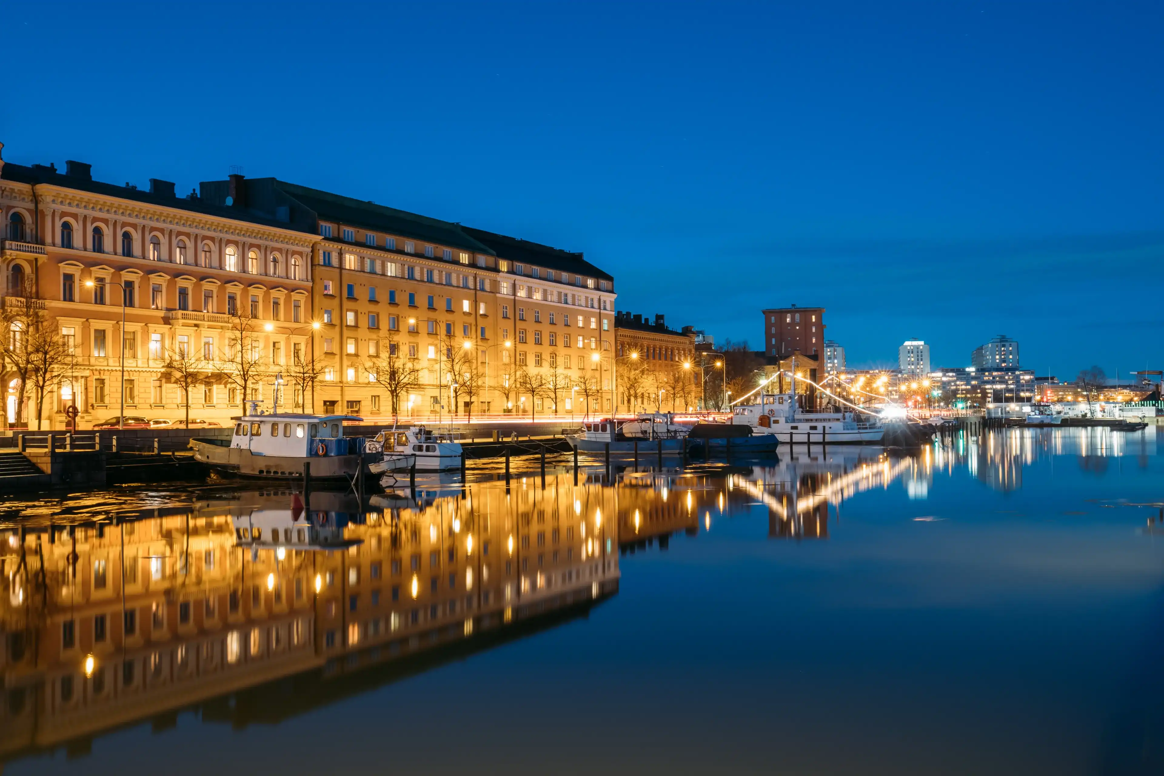 Helsinki, Finland. View Of Pier With Boats And Pohjoisranta Street In Evening Night Illuminations. Helsinki, Finland. View Of Pier With Boats And Pohjoisranta Street In Evening Night Illuminations.