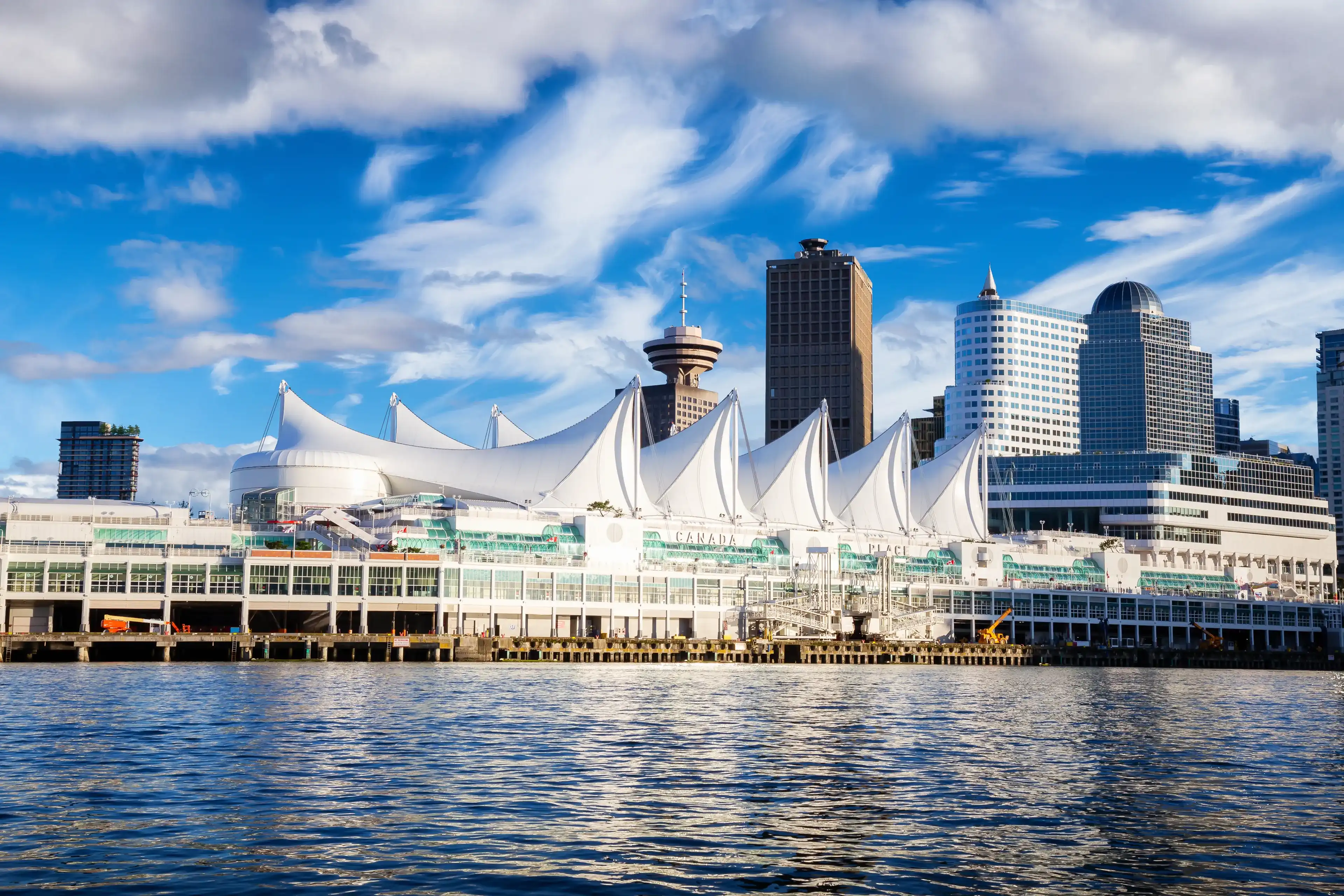 Canada Place and commercial buildings in Downtown Vancouver Viewed from water during Blue Sky Sunny Day. British Columbia, Canada. Urban Modern City Landmark Canada Place and commercial buildings in Downtown Vancouver Viewed from water during Blue Sky Sunny Day. British Columbia, Canada. Urban Modern City Landmark