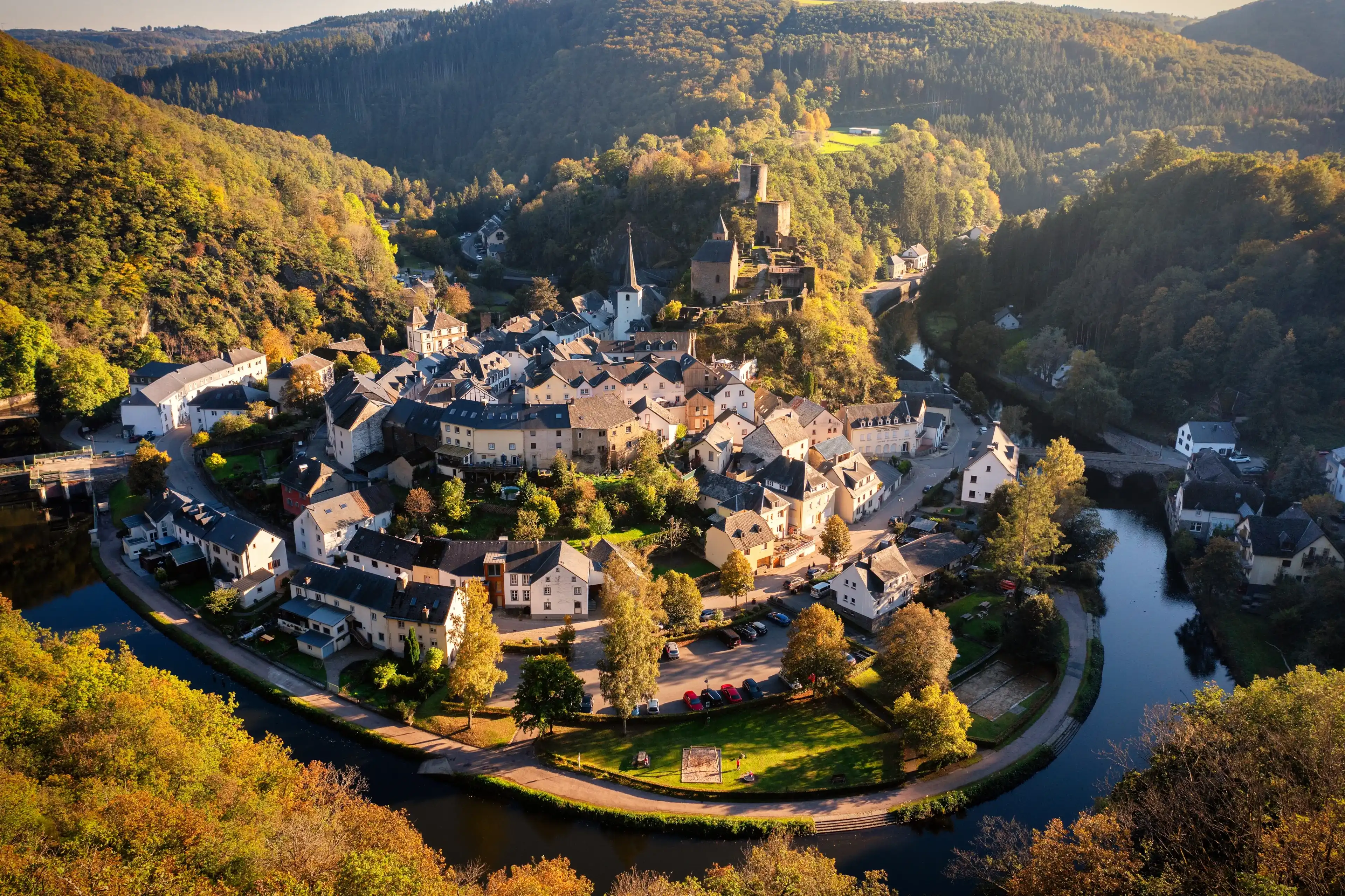Aerial view of Esch-sur-Sure, medieval town in Luxembourg, dominated by castle, canton Wiltz in Diekirch. Forests of Upper-Sure Nature Park, meander of winding river Sauer, near Upper Sauer Lake. Aerial view of Esch-sur-Sure, medieval town in Luxembourg, dominated by castle, canton Wiltz in Diekirch. Forests of Upper-Sure Nature Park, meander of winding river Sauer, near Upper Sauer Lake.