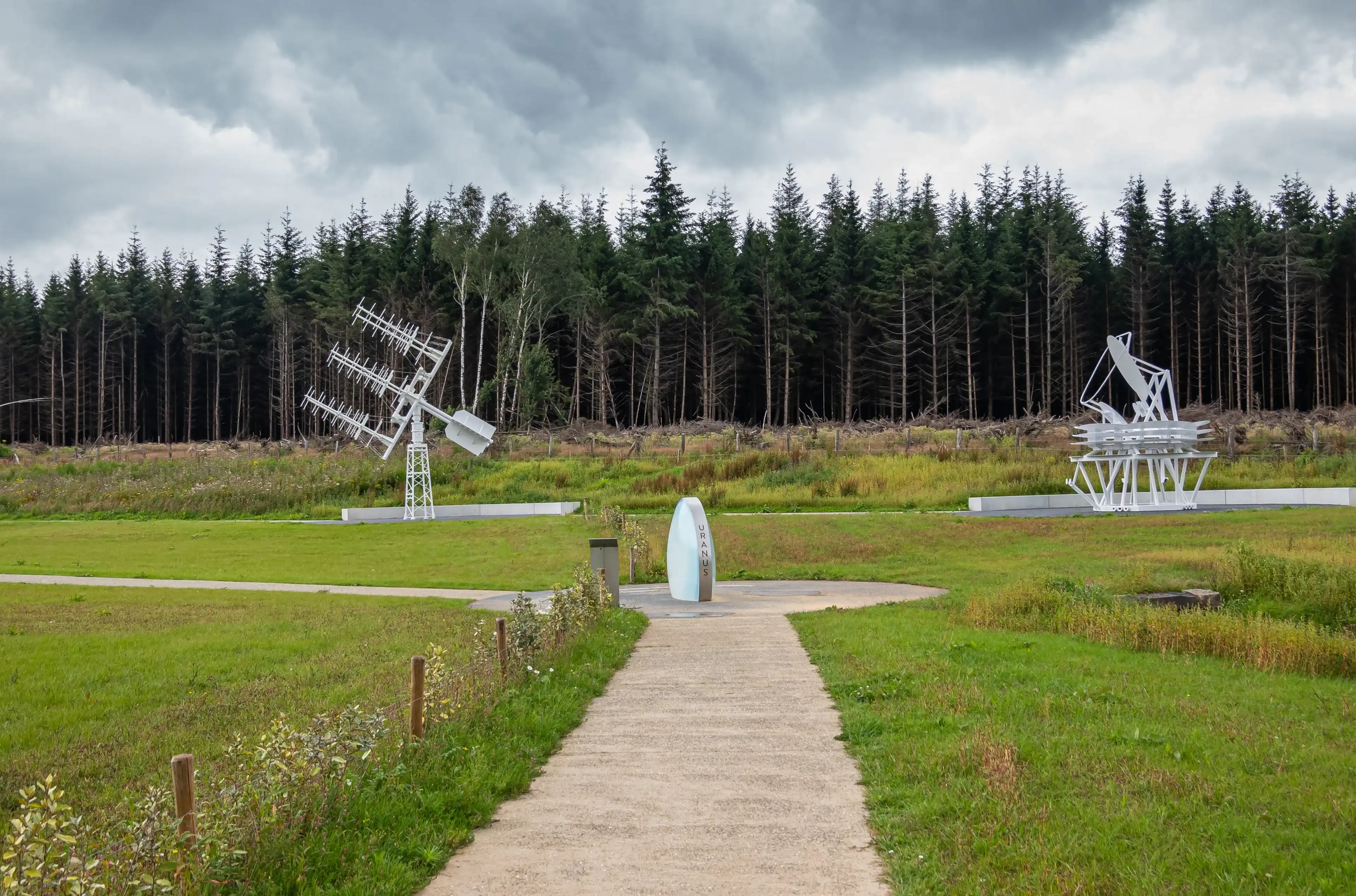 Transinne, Wallonia, Belgium - August 10, 2021: Euro Space Center. Uranus symbol and the Planck Mock Up and Yagi Antennas under rainy cloudscape. Dark green forest in back. Transinne, Wallonia, Belgium - August 10, 2021: Euro Space Center. Uranus symbol and the Planck Mock Up and Yagi Antennas under rainy cloudscape. Dark green forest in back.